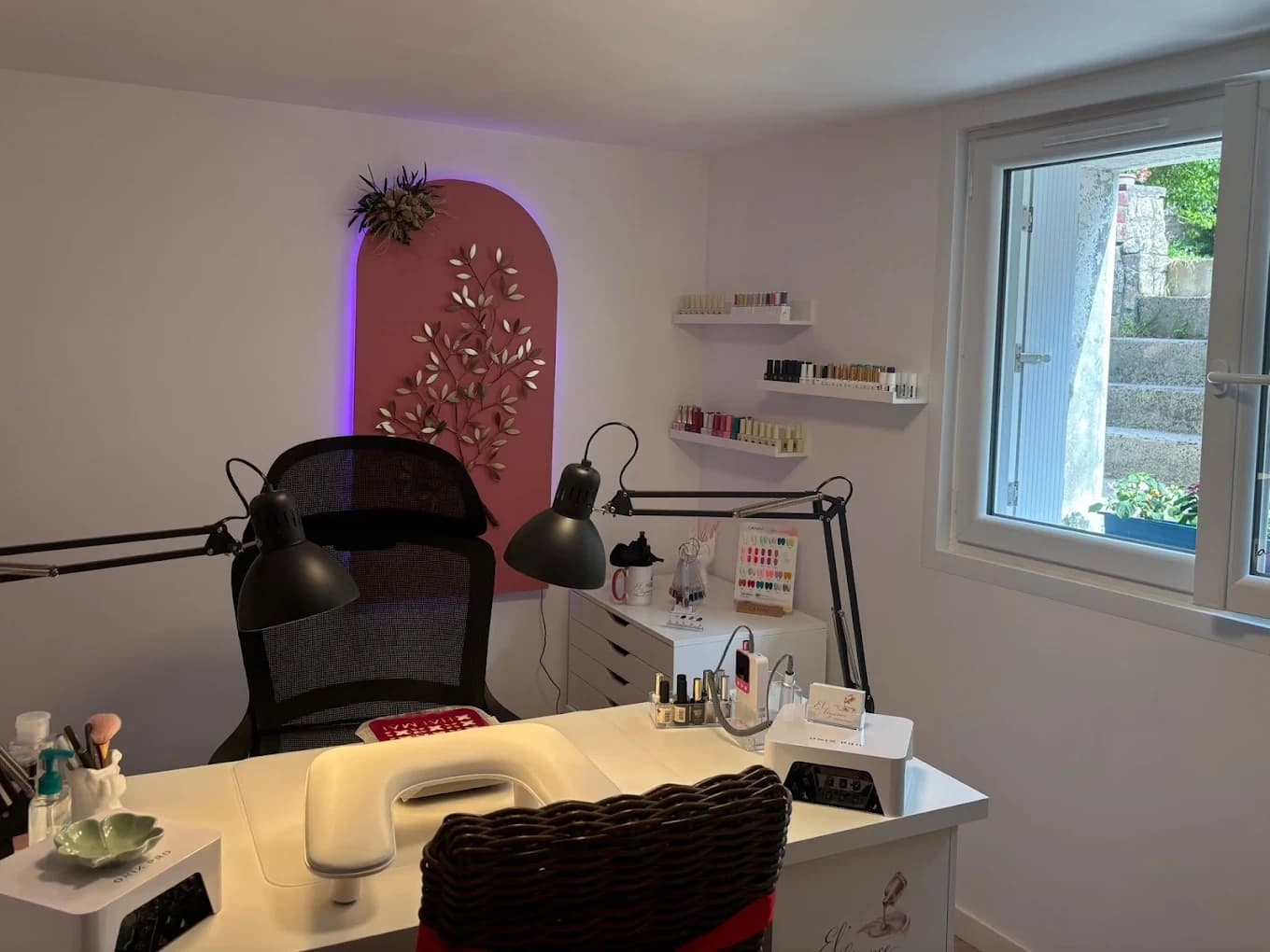 Un espace de manucure avec un bureau, des lampes et une décoration florale.